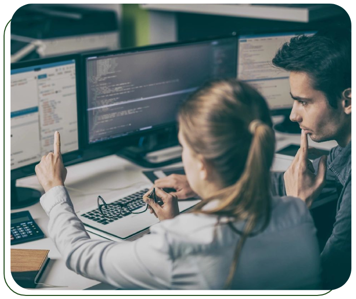 Two people sitting at a table with computers.