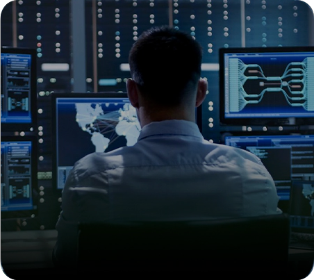 A man sitting in front of multiple computer monitors.