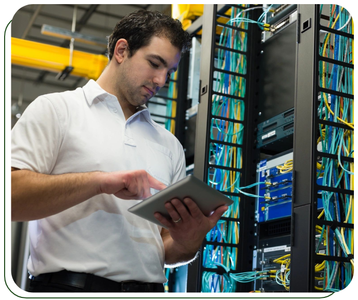 A man holding an ipad in front of server racks.